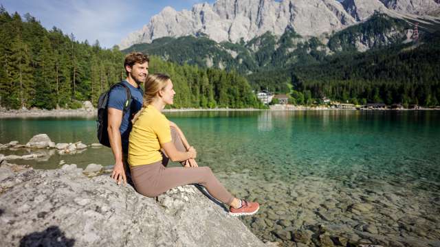 Paar sitzt am Eibsee blickt auf die Zugspitze